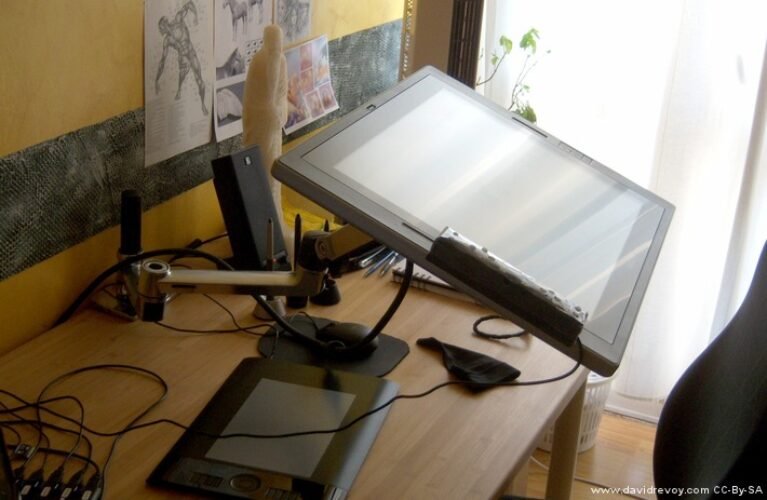 Chrome Ergotron LX arm with extra extension supporting a Cintiq display; extension and display are separate accessories
